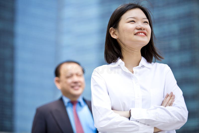 Young female Asian executive and senior Asian businessman smiling portrait