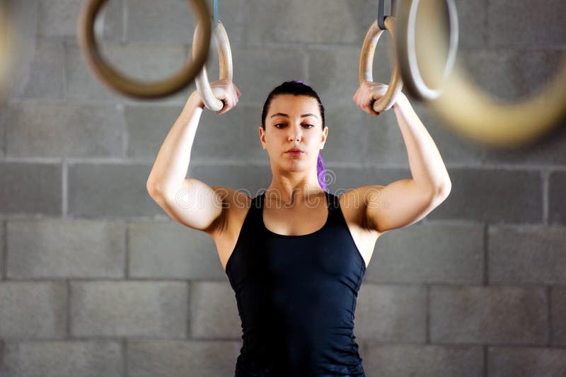 Young female athlete concentrating before working out on the rings psyching herself up to begin her exercise routine inside a gym. Young female athlete concentrating before working out on the rings psyching herself up to begin her exercise routine inside a gym