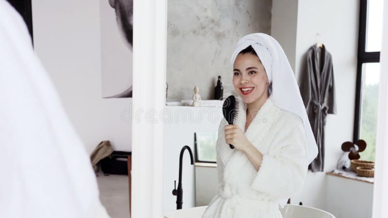 Young female in bathrobe spending morning at bathroom