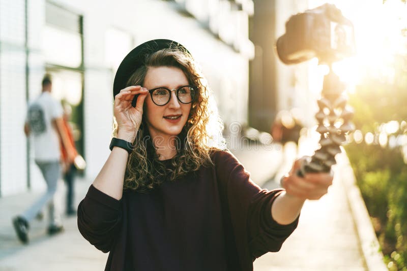 Young Female Blogger in Trendy Glasses and Hat Walks on City Street ...