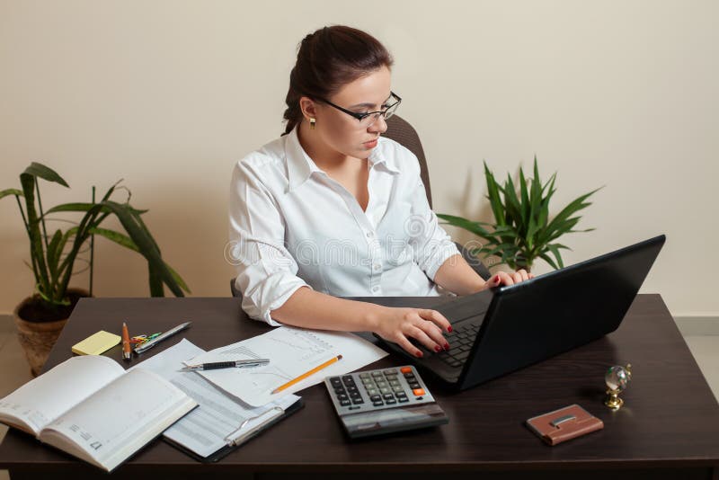 Female bookkeeper in glasses using laptop