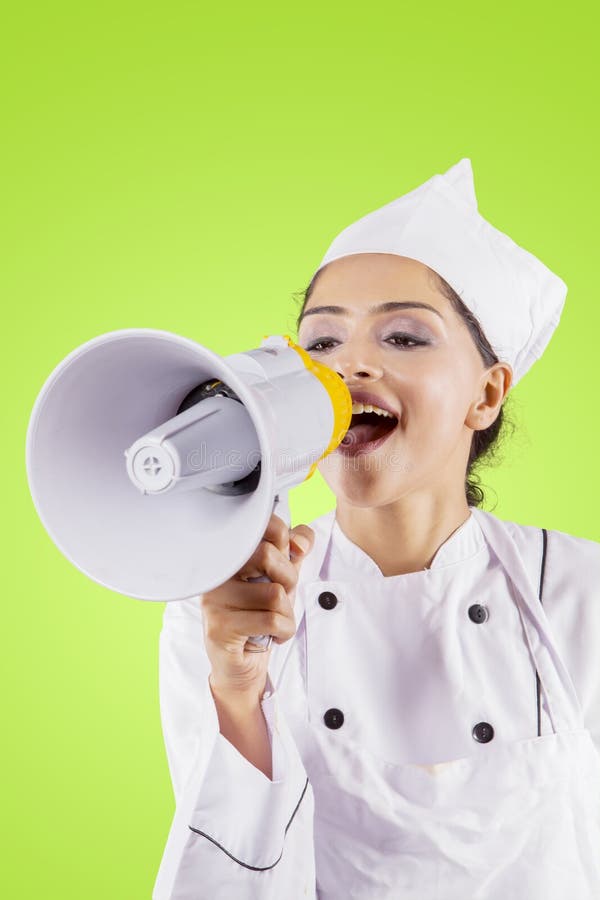 Young female chef using a megaphone on studio royalty free stock photography Young female chef using a megaphone on studio royalty free stock photography