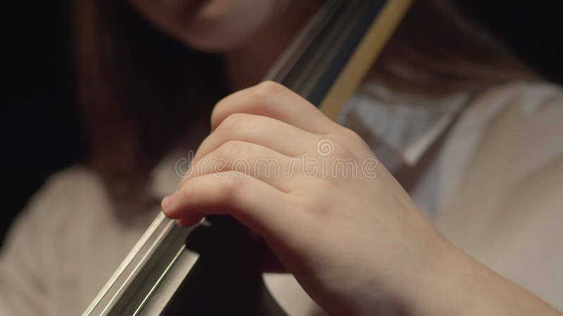 Young female classical musician in a white shirt playing music on a cello. Closeup of a hand on a string instrument stock video