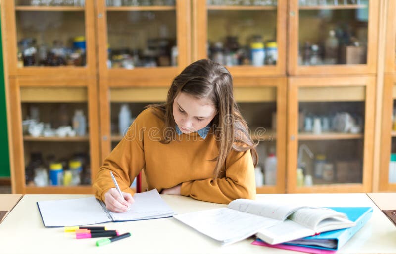 Mladá žena studentka v hodině chemie, psaní poznámek. Soustředěný student ve třídě.