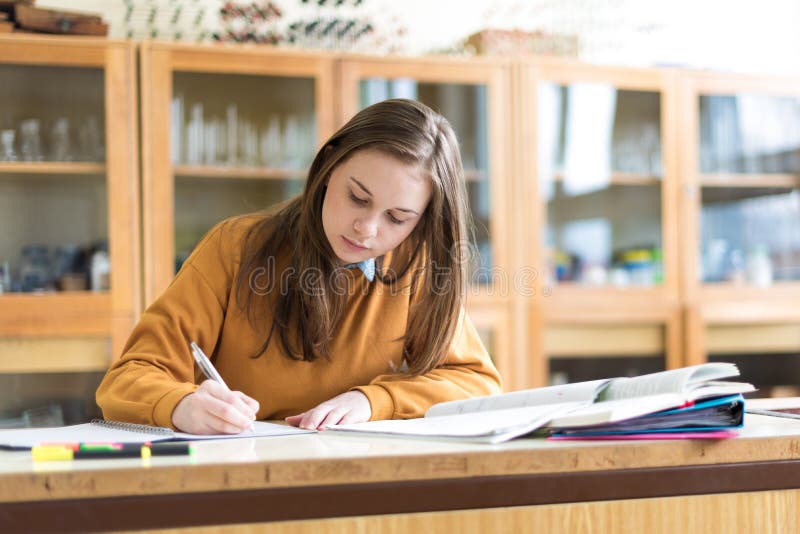 Mladá žena studentka v hodině chemie, psaní poznámek. Soustředěný student ve třídě.