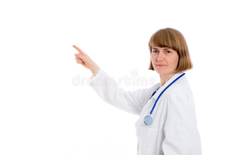Young female doctor in front of white background is pointing sideways. Young female doctor in front of white background is pointing sideways
