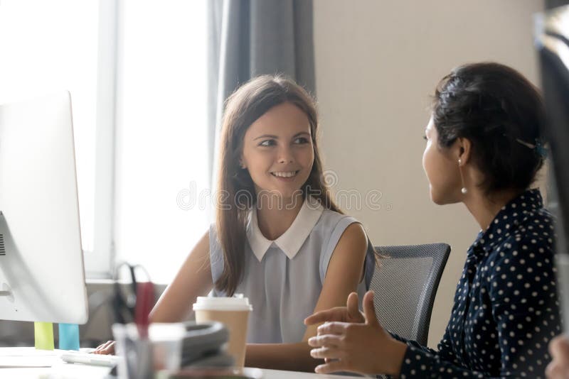 Young female employee talking with colleague at workplace stock images Young female employee talking with colleague at workplace stock images
