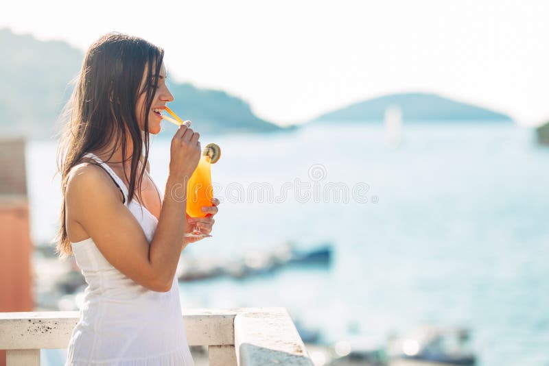 Young female enjoying a colourful cocktail on the panoramic view hotel terrace. Cold delicious cocktail smoothie stock image