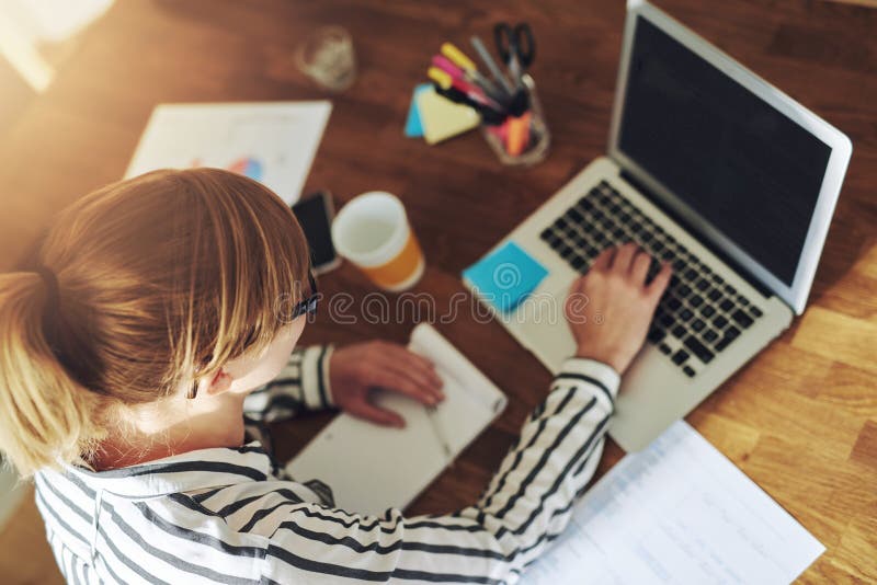 Joven una mujer emprendedor en negocios sobre el escritorio escribiendo sobre su computadora portátil computadora en oficina, más alto.