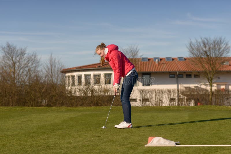 Young Female Golfer Putting Ball Towards Hole stock image Young Female Golfer Putting Ball Towards Hole stock image
