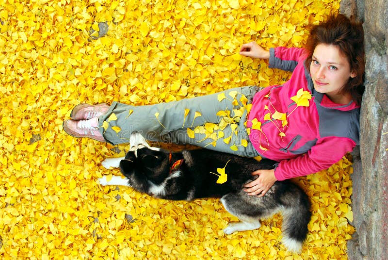 Young female and her dog in fallen leaves