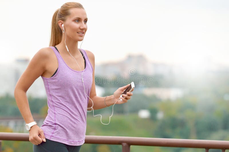 Young female joger is runing and listening to music during the run