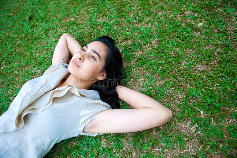 Young female laying on the grass, thinking