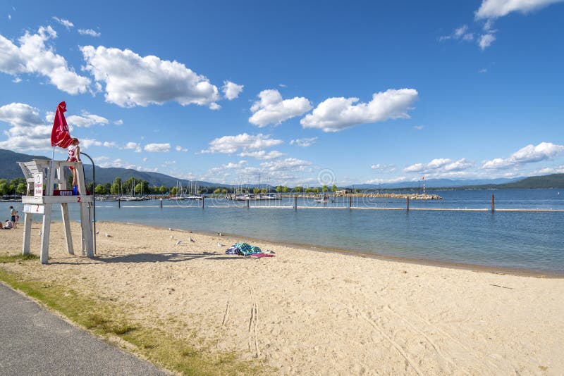 A young female lifeguard stands on duty at a lifeguard station along the sandy city beach at Sandpoint, Idaho stock photo A young female lifeguard stands on duty at a lifeguard station along the sandy city beach at Sandpoint, Idaho stock photo