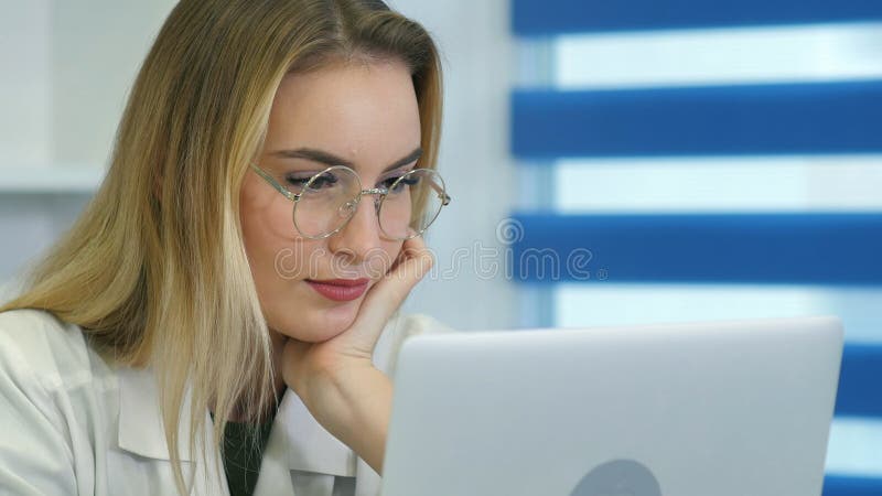 Young female nurse in glasses using laptop at desk in medical office royalty free stock image Young female nurse in glasses using laptop at desk in medical office royalty free stock image
