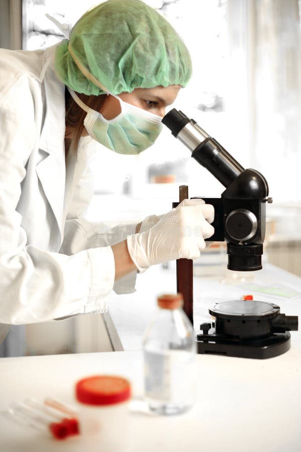 Young female researcher with microscope stock photography