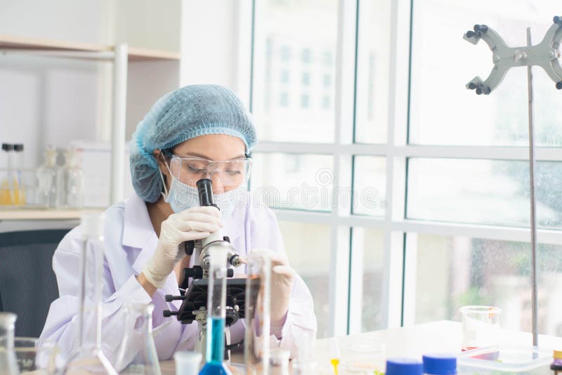 Young female scientist in protective glasses and gloves,use microscope to conduct research in laboratory,concept test sample antibiotic and future food used medical and science development for people