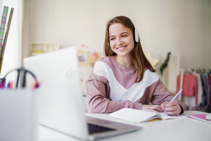 Young female student sitting at the table, using laptop when studying.