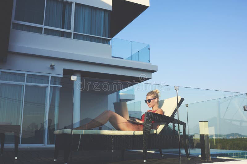 Young female successful freelancer in sunglasses is using laptop computer for remote work royalty free stock image Young female successful freelancer in sunglasses is using laptop computer for remote work royalty free stock image