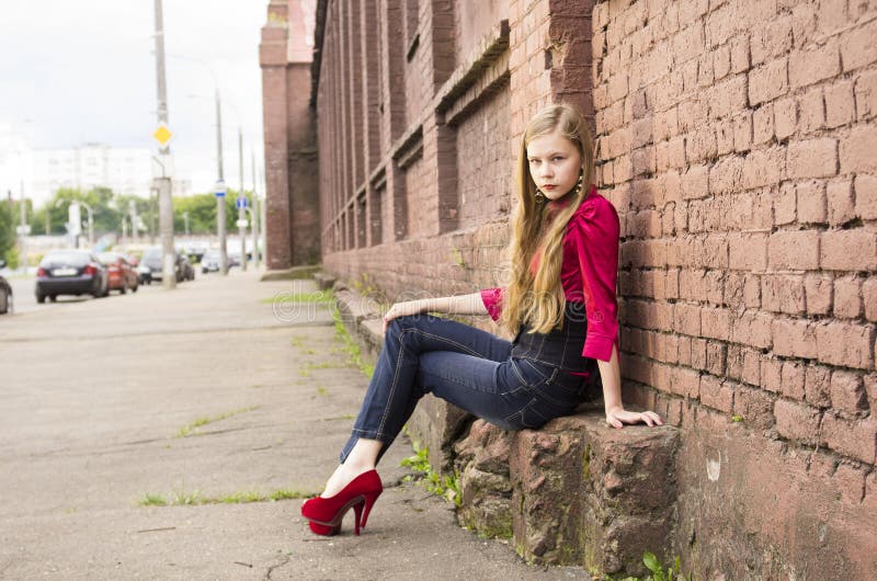 Young female teen girl pose against a brick wall.