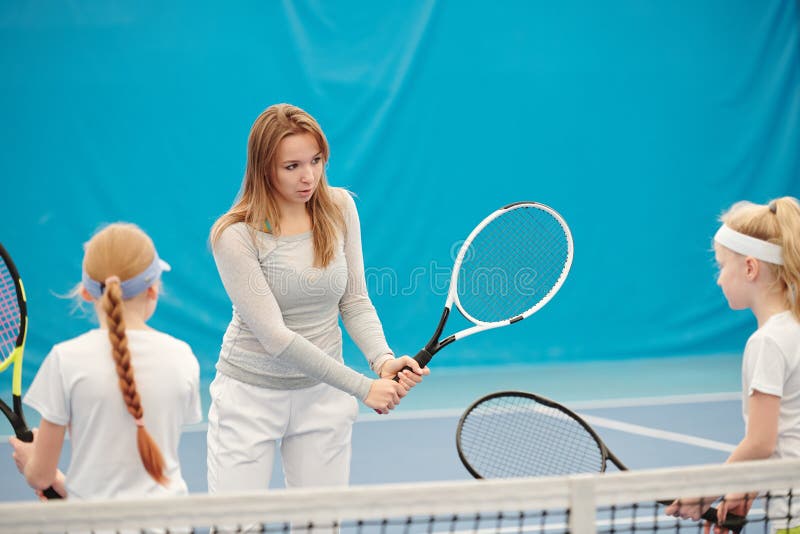 Young Female Tennis Trainer in Activewear Holding Racket Ready To Push ...