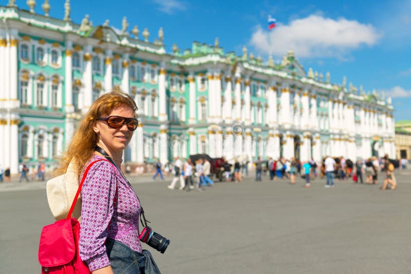 Young female tourist passes the Winter Palace in Saint Petersburg