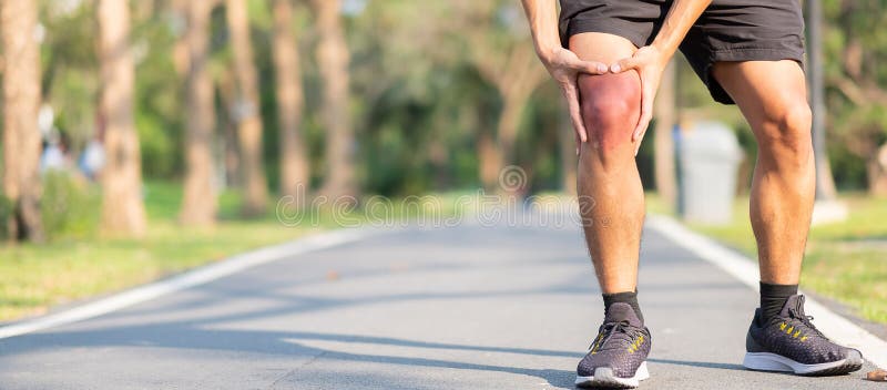 Young fitness man holding his sports leg injury. muscle painful during training. Asian runner having knee ache and problem after stock photo Young fitness man holding his sports leg injury. muscle painful during training. Asian runner having knee ache and problem after stock photo