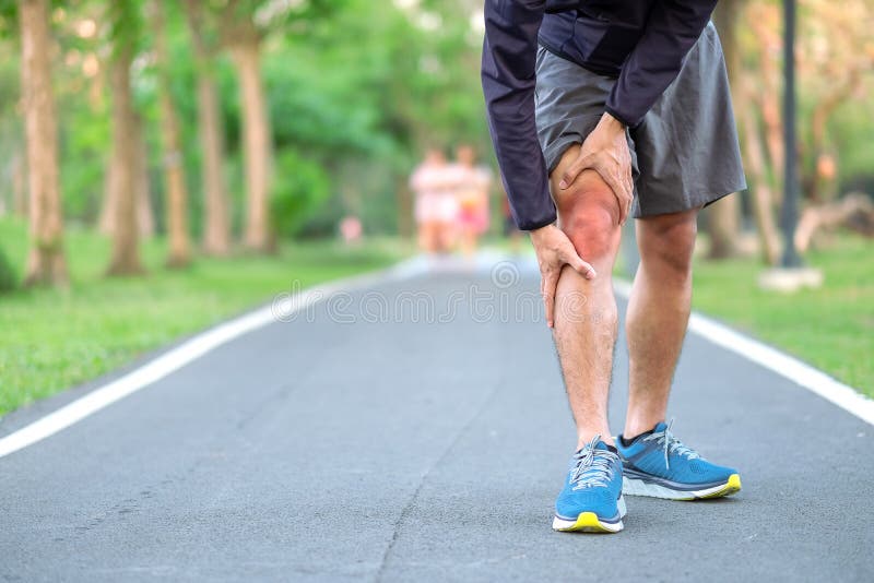 Young fitness man holding his sports leg injury. muscle painful during training. Asian runner having knee ache and problem after