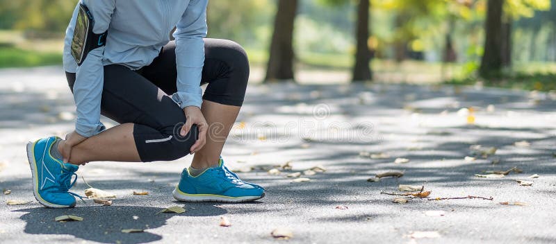 Young fitness woman holding his sports leg injury, muscle painful during training. Asian runner having calf ache and problem after running and exercise outside in summer