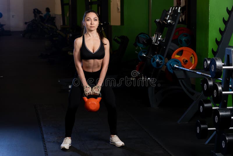 Young fitness woman swinging the kettlebell during crossfit training. Athletic girl doing workout in a fitness center royalty free stock image Young fitness woman swinging the kettlebell during crossfit training. Athletic girl doing workout in a fitness center royalty free stock image
