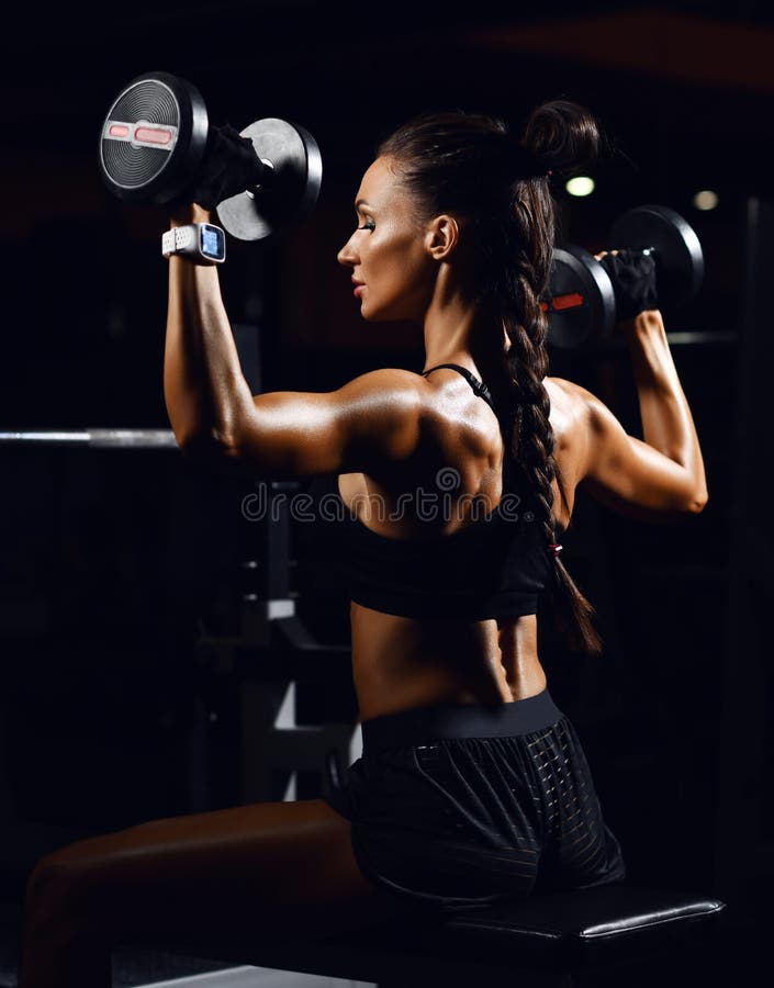 Young fitness woman working out with dumbbells weight in Gym. Diet and weight loss concept