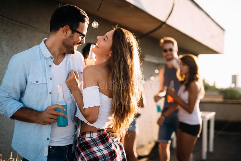 Young friends having fun at a rooftop party, playing the guitar, singing, dancing and drinking royalty free stock images Young friends having fun at a rooftop party, playing the guitar, singing, dancing and drinking royalty free stock images