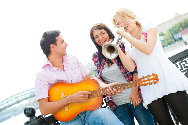 Young friends play the guitar and trumpet