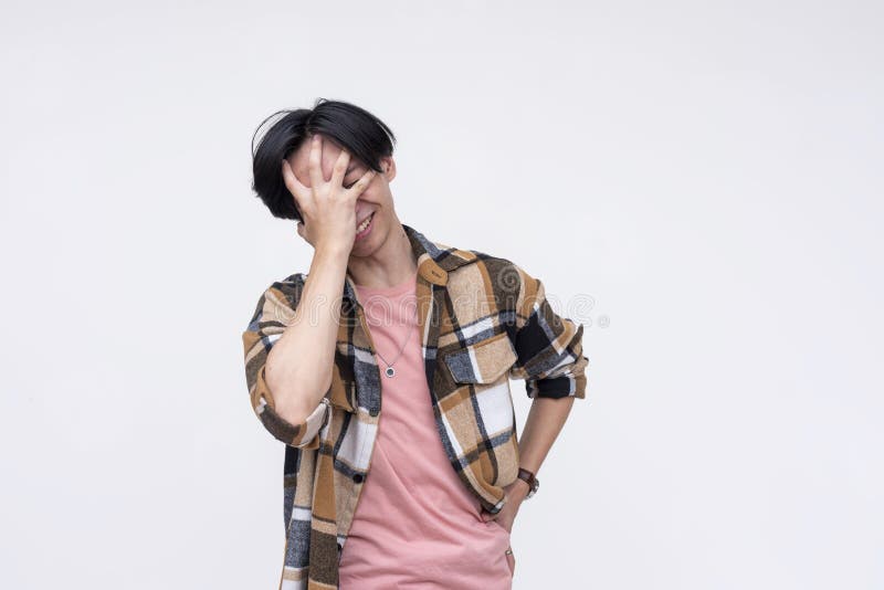 A young frustrated asian man face palms from stress. Screwing up and realizing his blunders. Annoyed about his current situation. stock photo