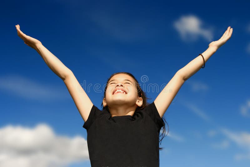 Young girl with both arms wide open, facing the bright sunshine against deep blue sky in the background, celebrating beauty of nature. Young girl with both arms wide open, facing the bright sunshine against deep blue sky in the background, celebrating beauty of nature.