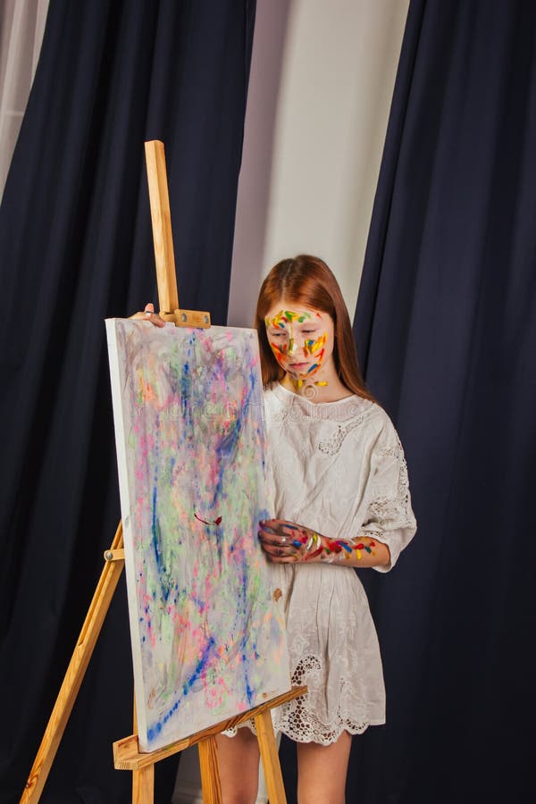Mladý z umělec v světlo bílý šaty, barvy obrázek na plátno v dílna.