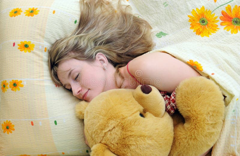 Young girl asleep in her bed with a teddy bear