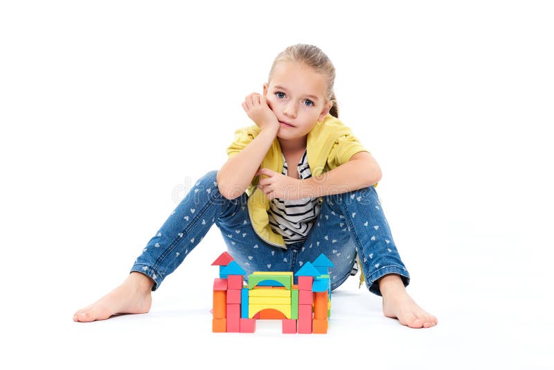 Young girl at behavior therapy, building a castle with wooden toy block. Child play therapy concept on white background.