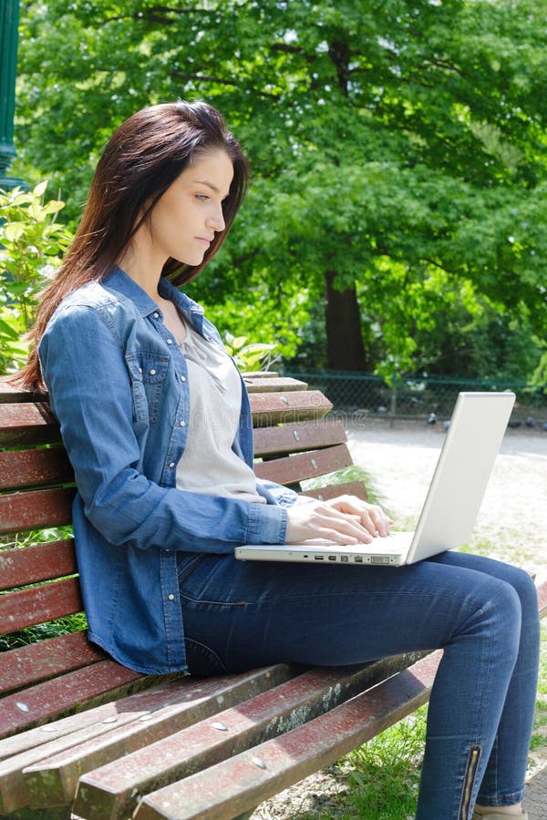 Young girl on bench with laptop royalty free stock image