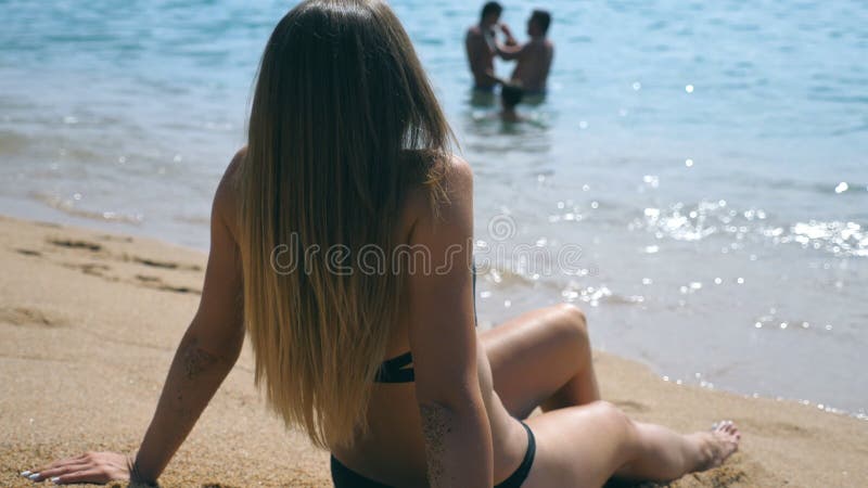 Young girl in bikini lying on sea beach and sunbathing. Beautiful unrecognizable woman relaxing on ocean shore during