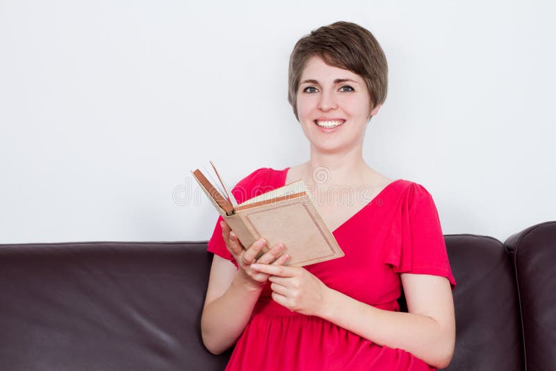 Young girl with book on brown sofa