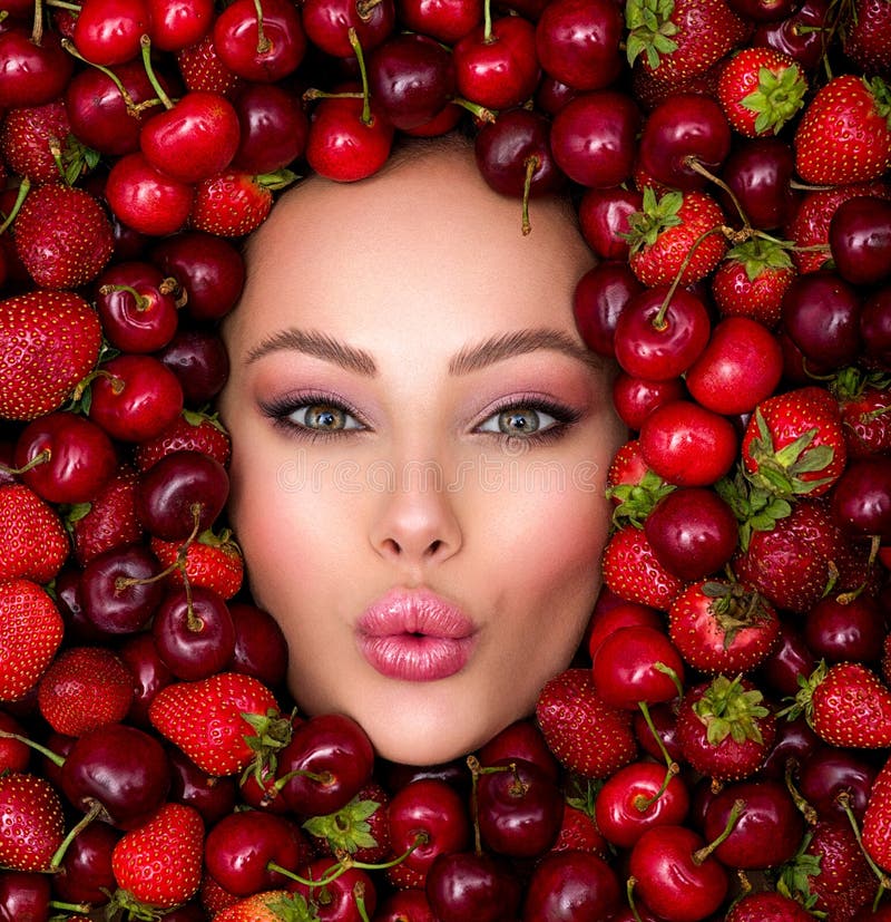 Young girl with bright makeup and a berry background. Beautiful caucasian woman. Attractive woman