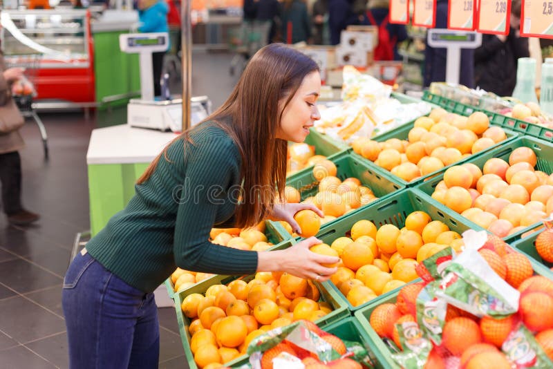 Young girl buys oranges in a grocery store