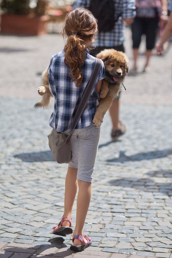 Young girl carries her puppy in the city