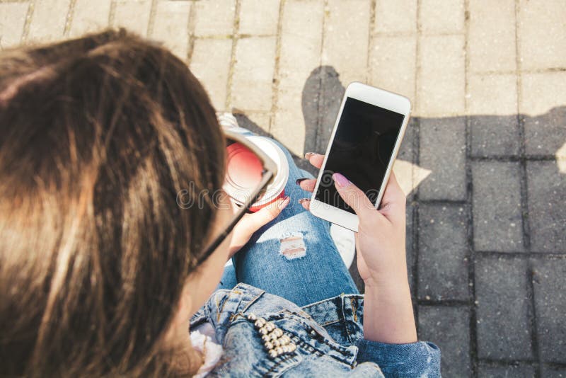 A young girl in a denim jacket walks down the street with coffee and a phone in her hands. Girl in glasses and a denim jacket on royalty free stock photos A young girl in a denim jacket walks down the street with coffee and a phone in her hands. Girl in glasses and a denim jacket on royalty free stock photos