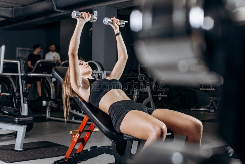 Premium Photo  Fit woman trains chest muscles doing bench press with  dumbbells in hands while lying on an incline bench in the gym