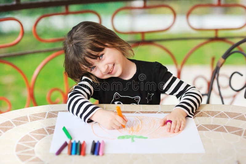 Young girl draws Halloween pumpkin outdoors