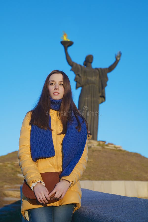 Young girl dressed in Ukrainian national colors against blue sky