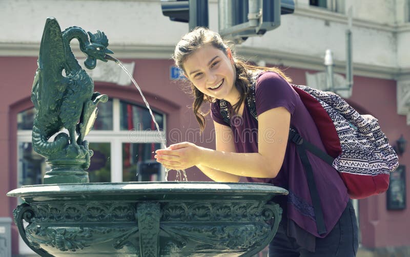 Young girl drinking water from the fountain