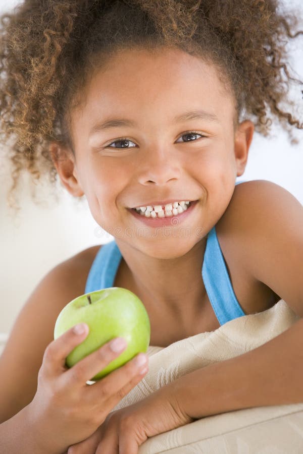 Young girl eating apple in living room